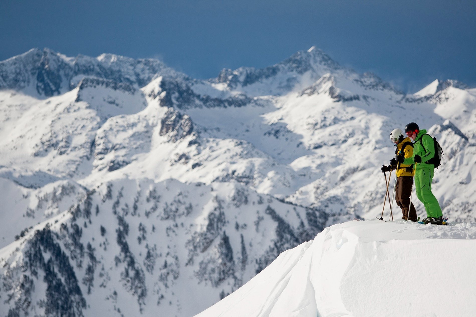 deux skieurs se tiennent au sommet d' une montagne enneigée