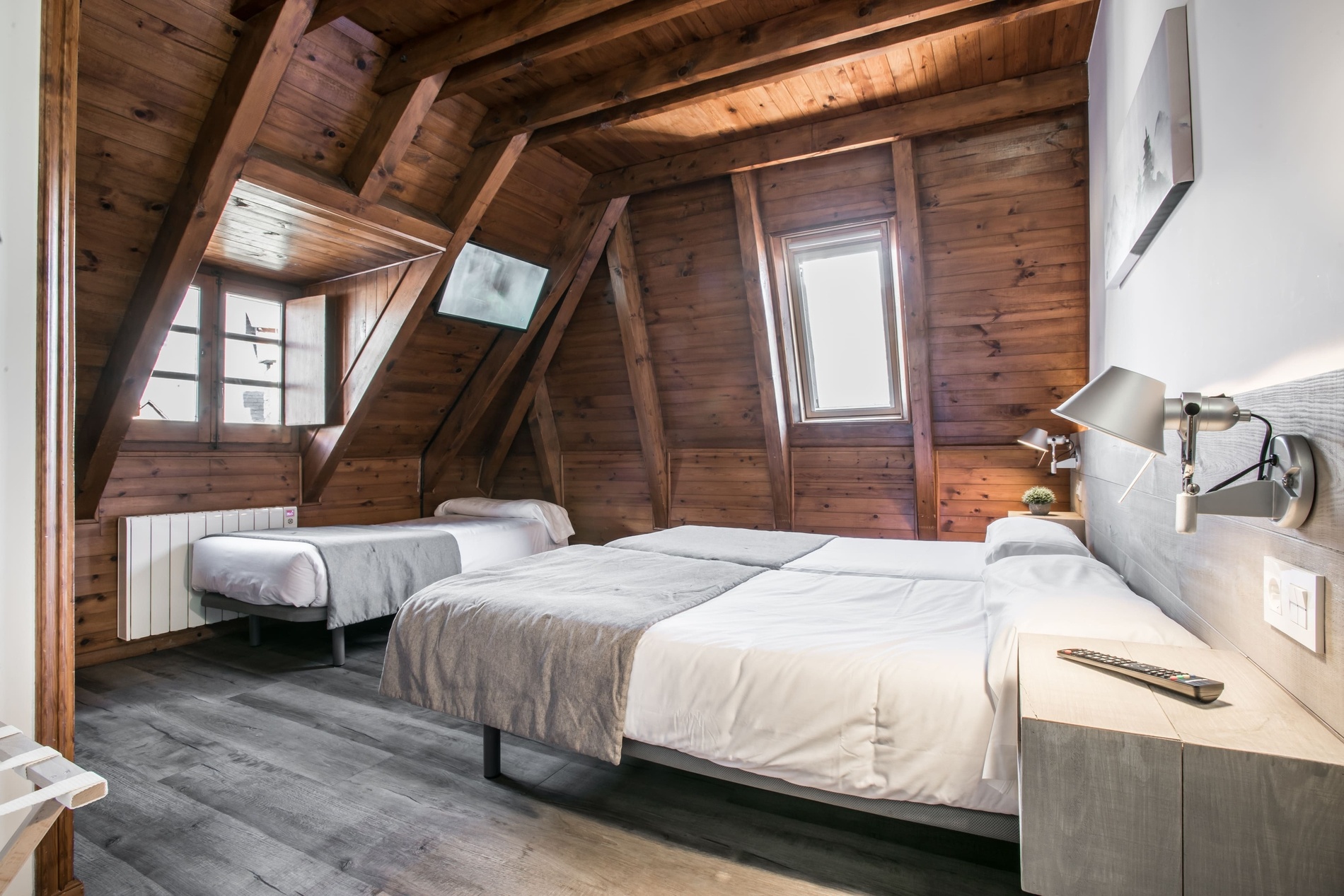 una habitació de fusta amb tres camas i un televisor