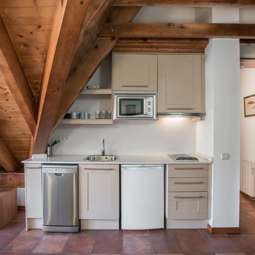 una pequeña cocina con gabinetes blancos y electrodomésticos de acero inoxidable