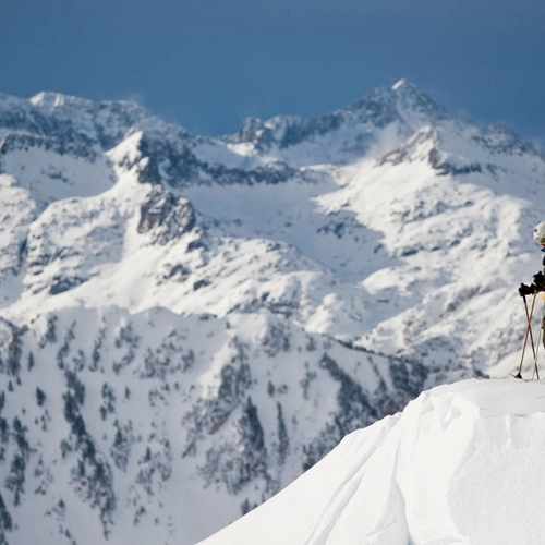 Des skieurs à SNO: Mont Romies surplombant des montagnes enneigées.