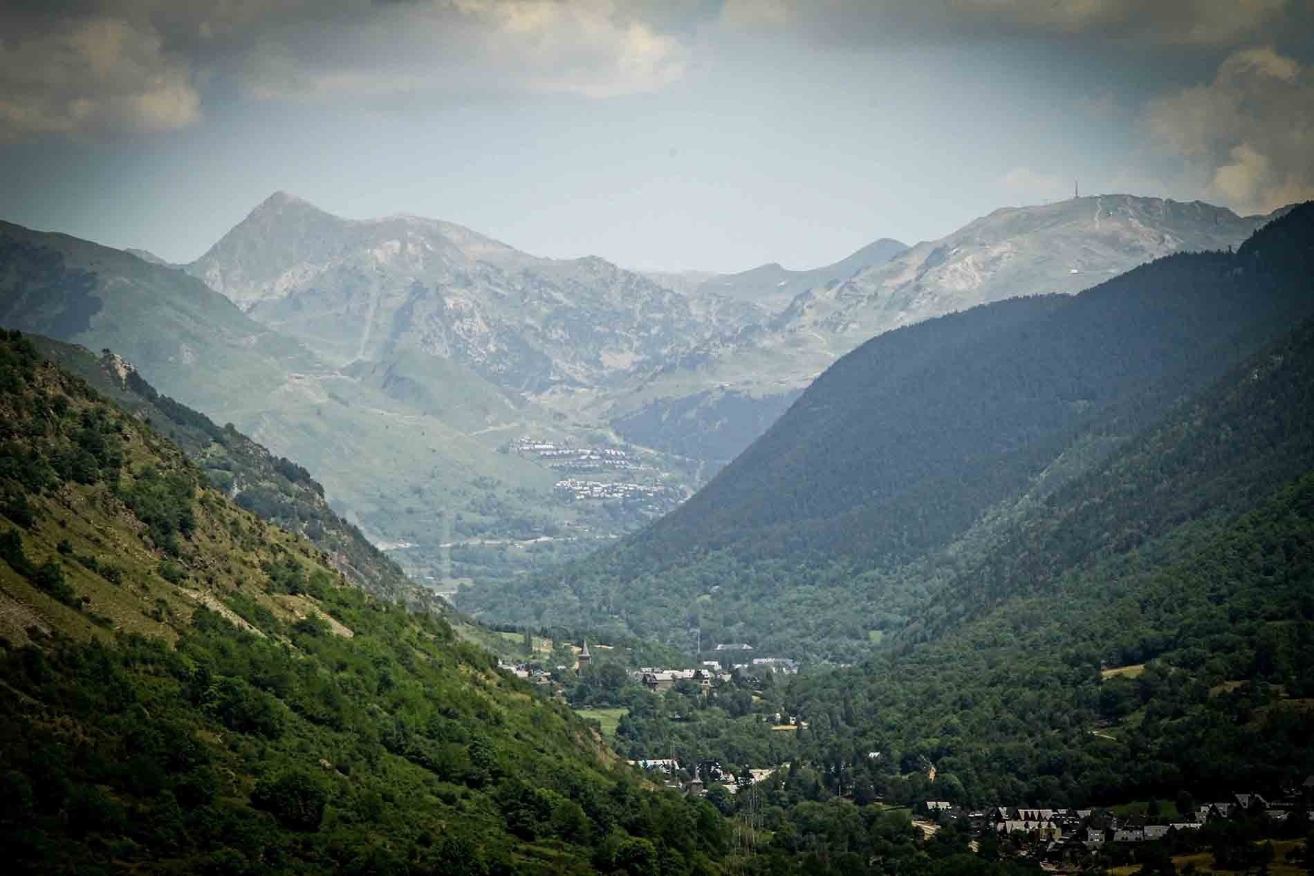 un paisatge d' una vall de montagna amb una ciutat al fons