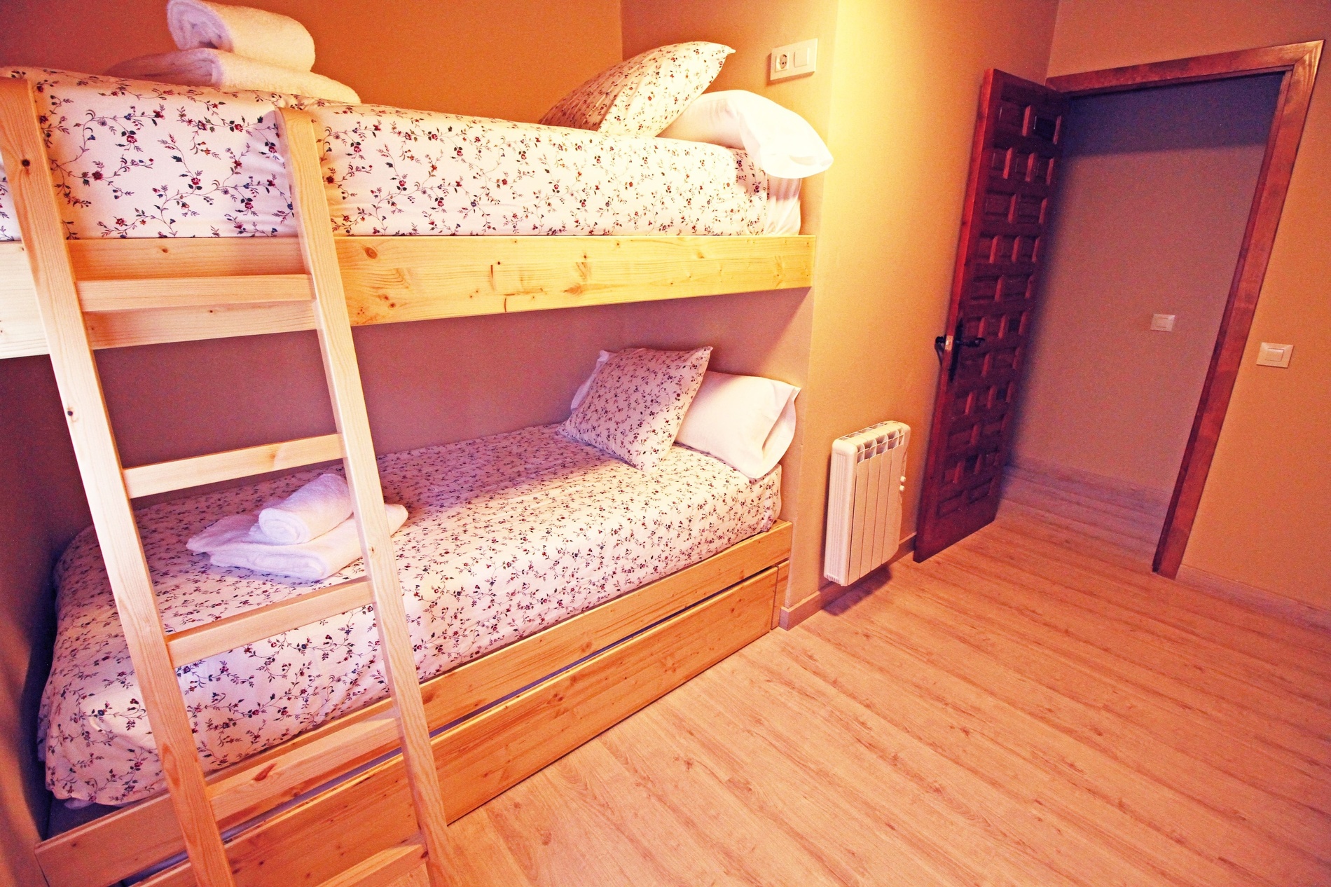 une chambre avec trois lits superposés et une porte en bois