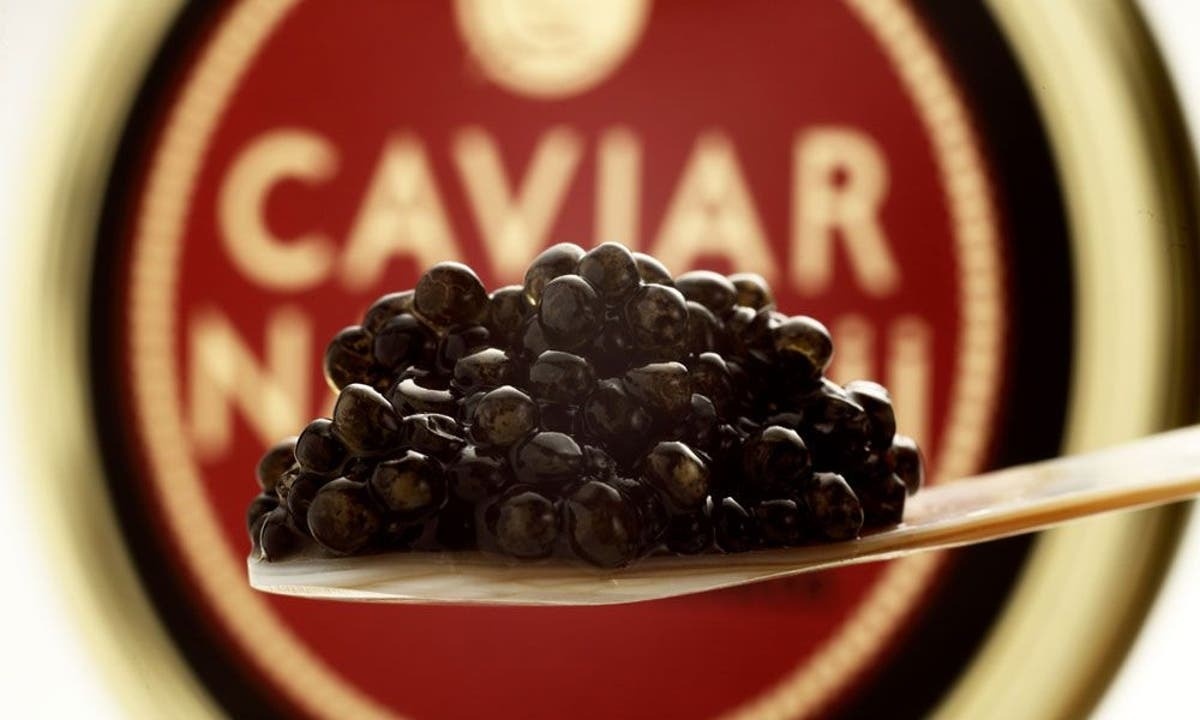 una cuchara llena de caviar frente a una etiqueta de caviar