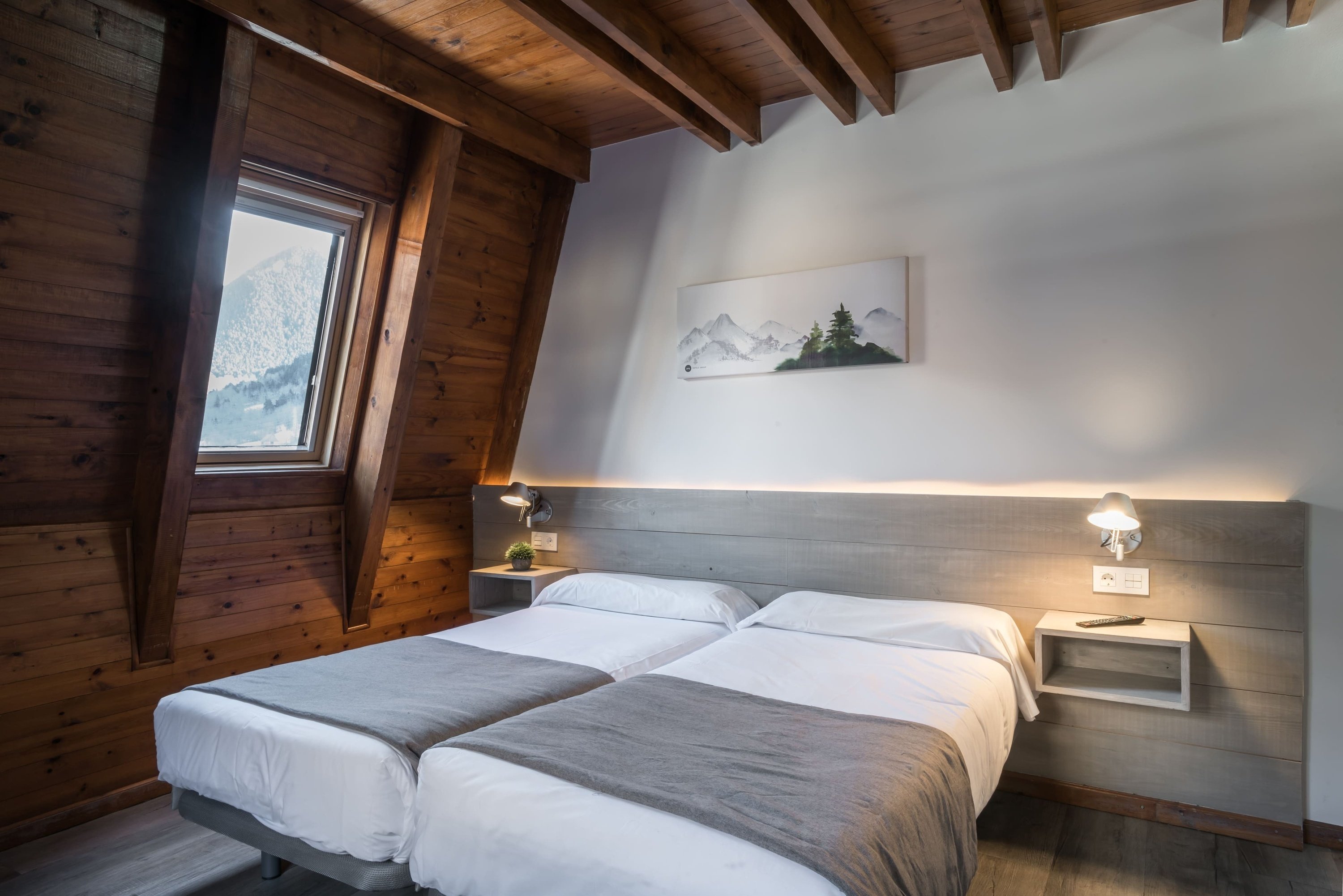 una habitación con dos camas y una pintura de montañas en la pared