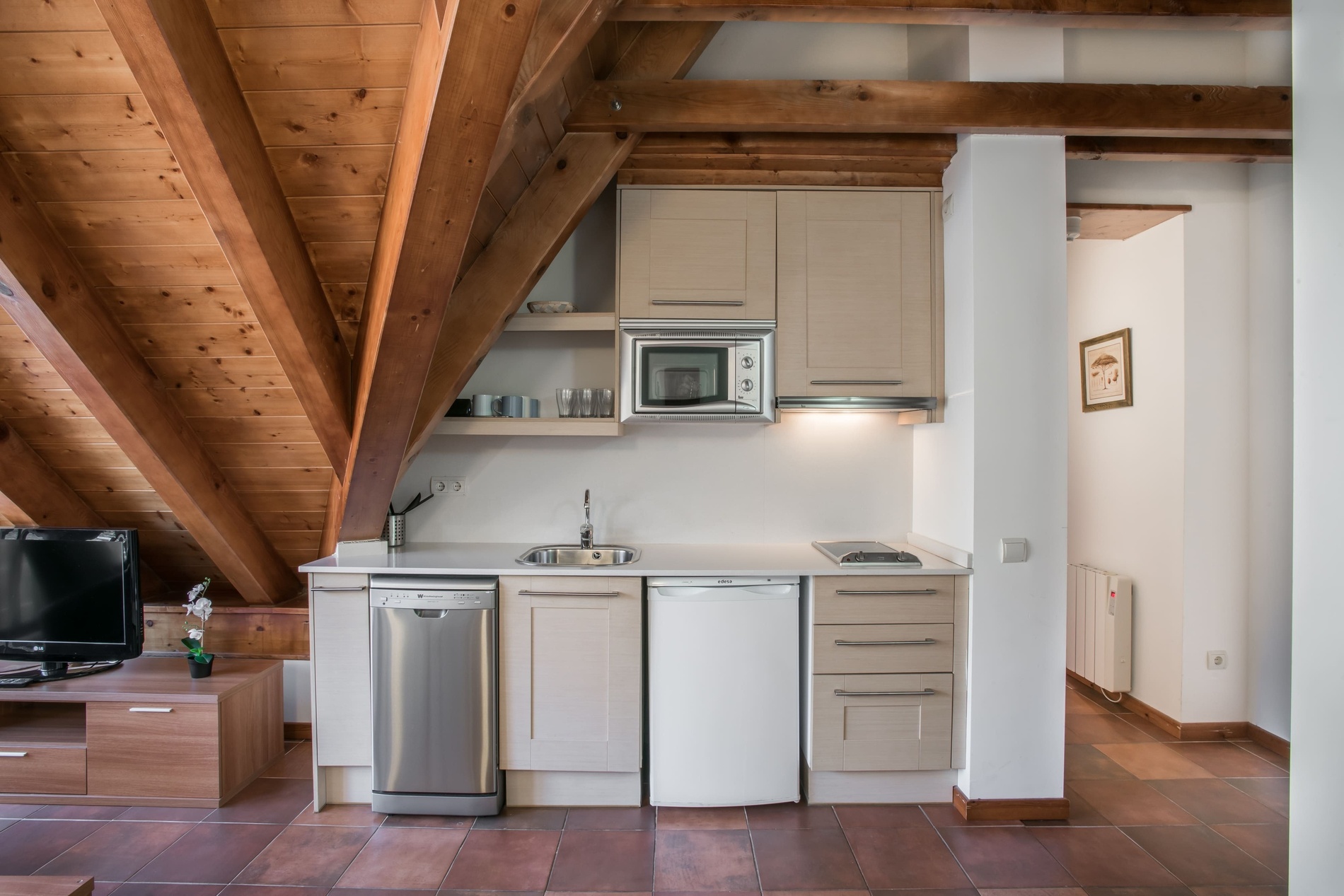 una pequeña cocina con gabinetes blancos y electrodomésticos de acero inoxidable