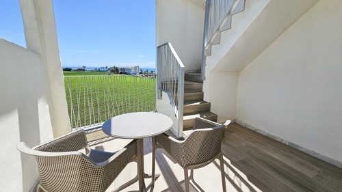 a balcony with a table and chairs and stairs leading up to the second floor