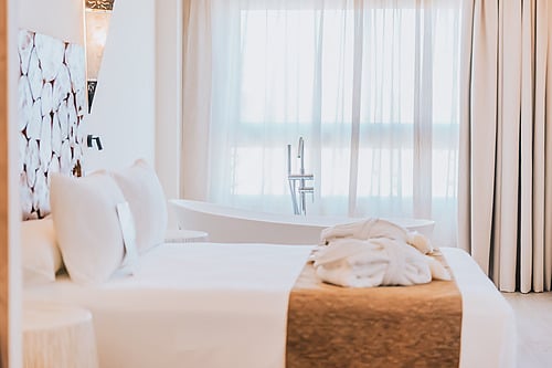Luxury hotel suite with a bed, bathtub, and sheer curtains. Qhotels: Zahara Beach & SPA