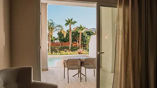 Ein luxuriöses Hotelzimmer mit Blick auf einen Pool und Palmen Qhotels: Zahara Beach & SPA