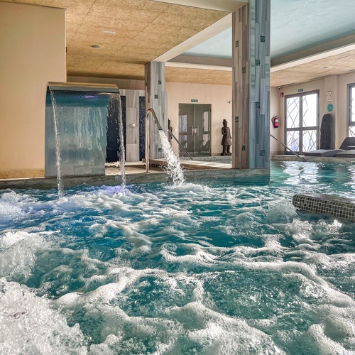 a large indoor swimming pool with wicker chairs around it