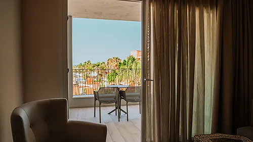 Balkon mit Tisch und Stühlen, Blick auf Resort und Palmen - Qhotels: Zahara Beach & SPA