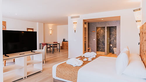 Spacious hotel suite with modern amenities: bed, TV, dining area, and ensuite bathroom. Qhotels: Zahara Beach & SPA