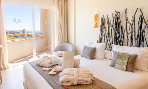 hay dos camas de madera en la terraza con vistas al océano .