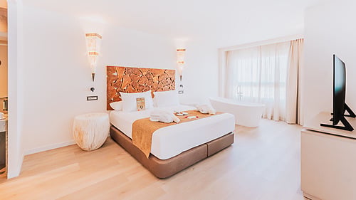 Luxury hotel suite with a king-size bed, freestanding bathtub, and modern amenities. Qhotels: Zahara Beach & SPA
