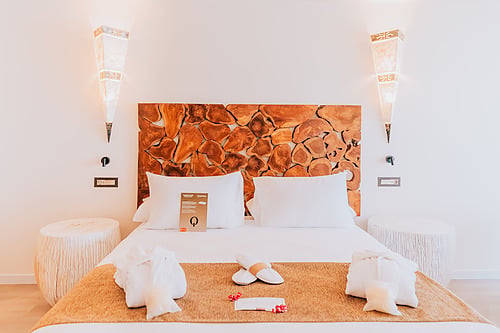 Luxurious hotel room with a wooden headboard, plush bedding, and ambient lighting. Qhotels: Zahara Beach & SPA