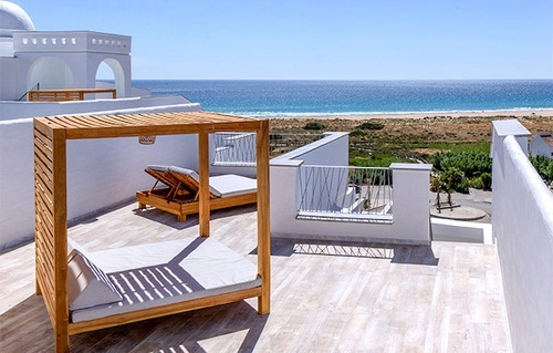 a canopy bed sits on a balcony overlooking the ocean