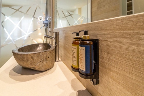 a bathroom with a sink and three bottles of mana soap