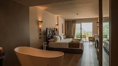 Luxuriöses Hotelzimmer mit freistehender Badewanne, Bett und Meerblick-Balkon. Qhotels: Zahara Beach & SPA