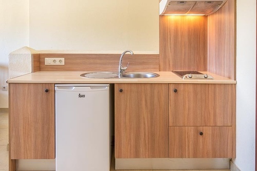 una pequeña cocina con gabinetes de madera y una nevera pequeña