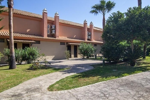 a brick walkway leads to a building with a tiled roof