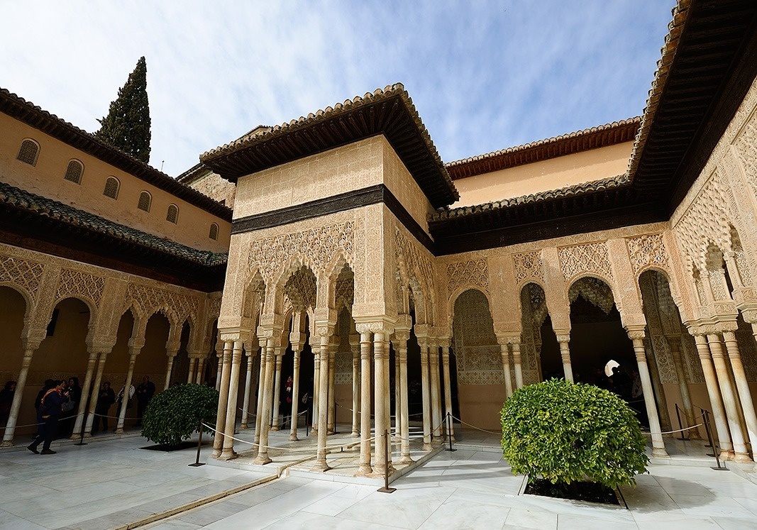 un edificio con columnas y arcos está rodeado de árboles