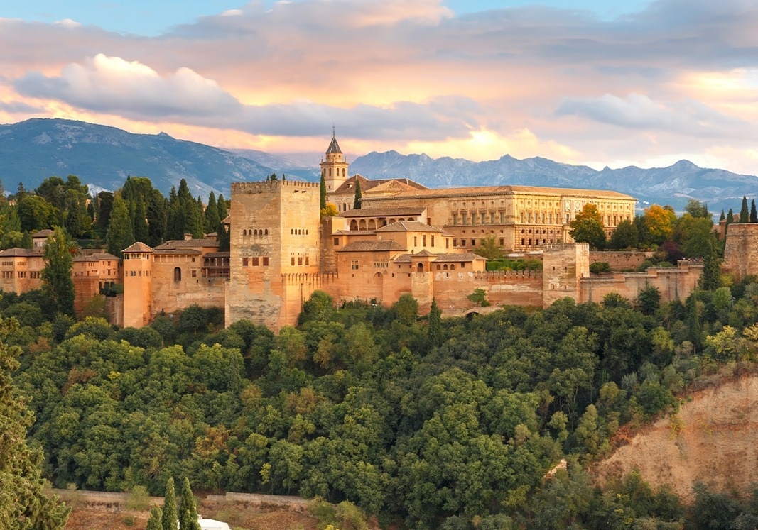 un gran castillo está rodeado de árboles y montañas