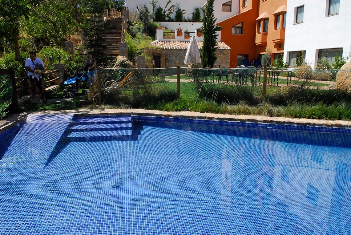 a man holding a baby stands next to a swimming pool