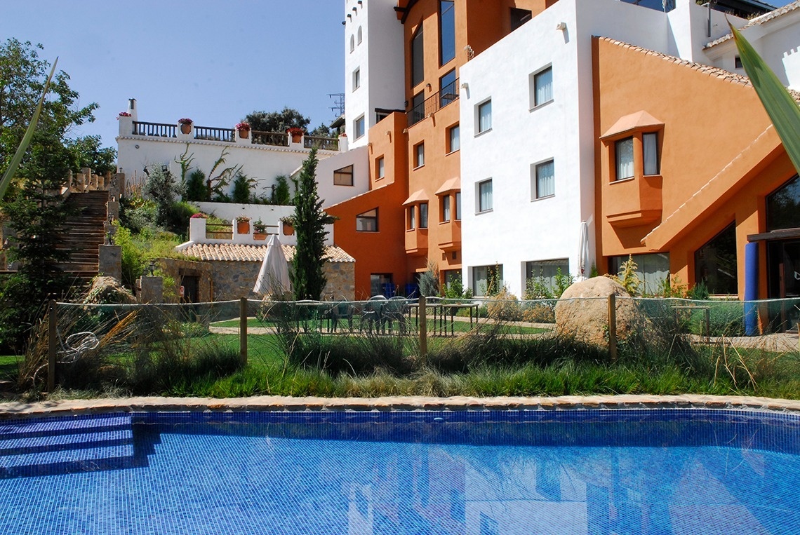 una piscina azul está al lado de un edificio naranja y blanco