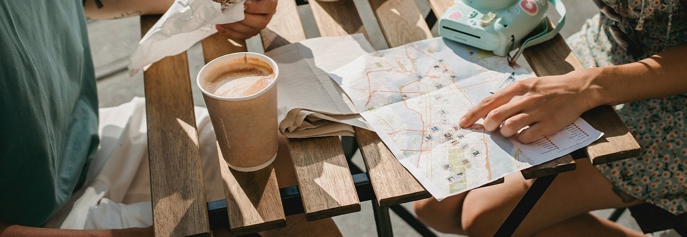 dos personas están sentadas en una mesa de madera mirando un mapa y una taza de café
