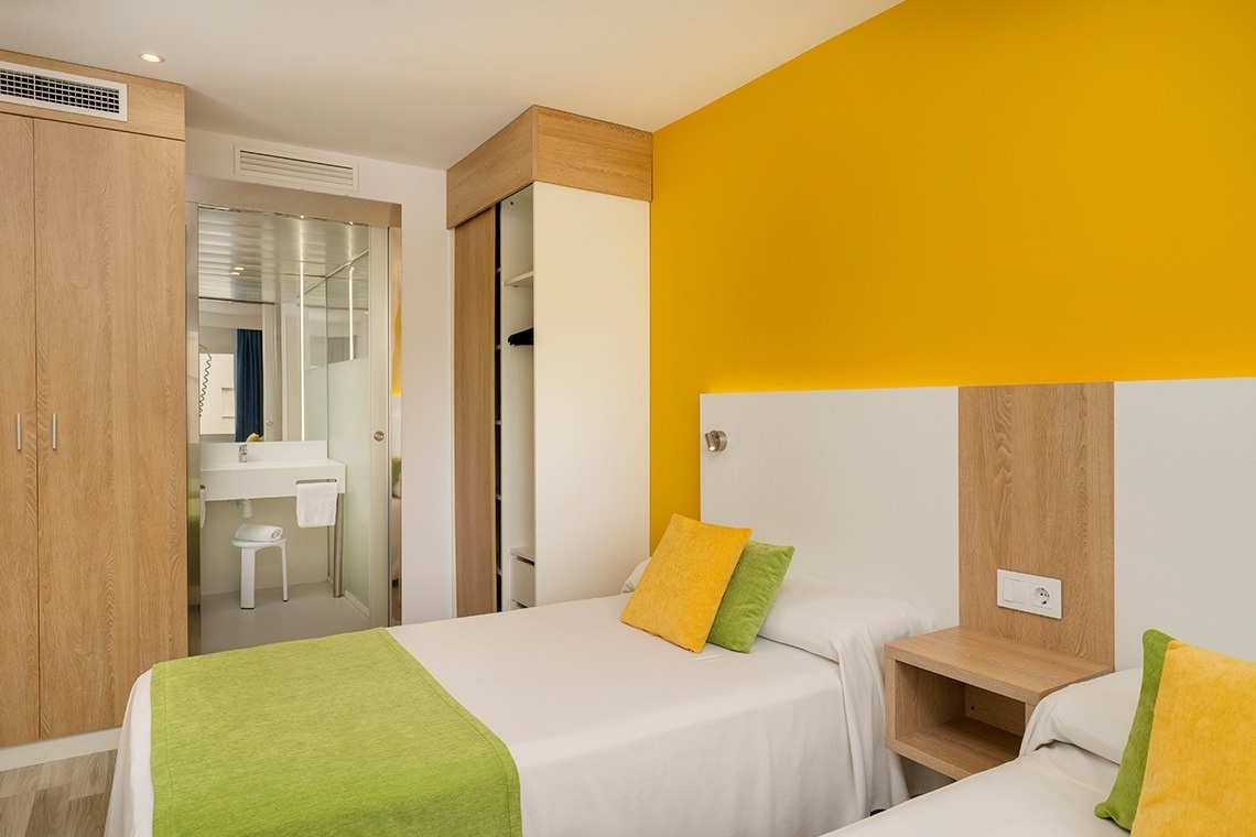 a bedroom with two beds and a yellow wall