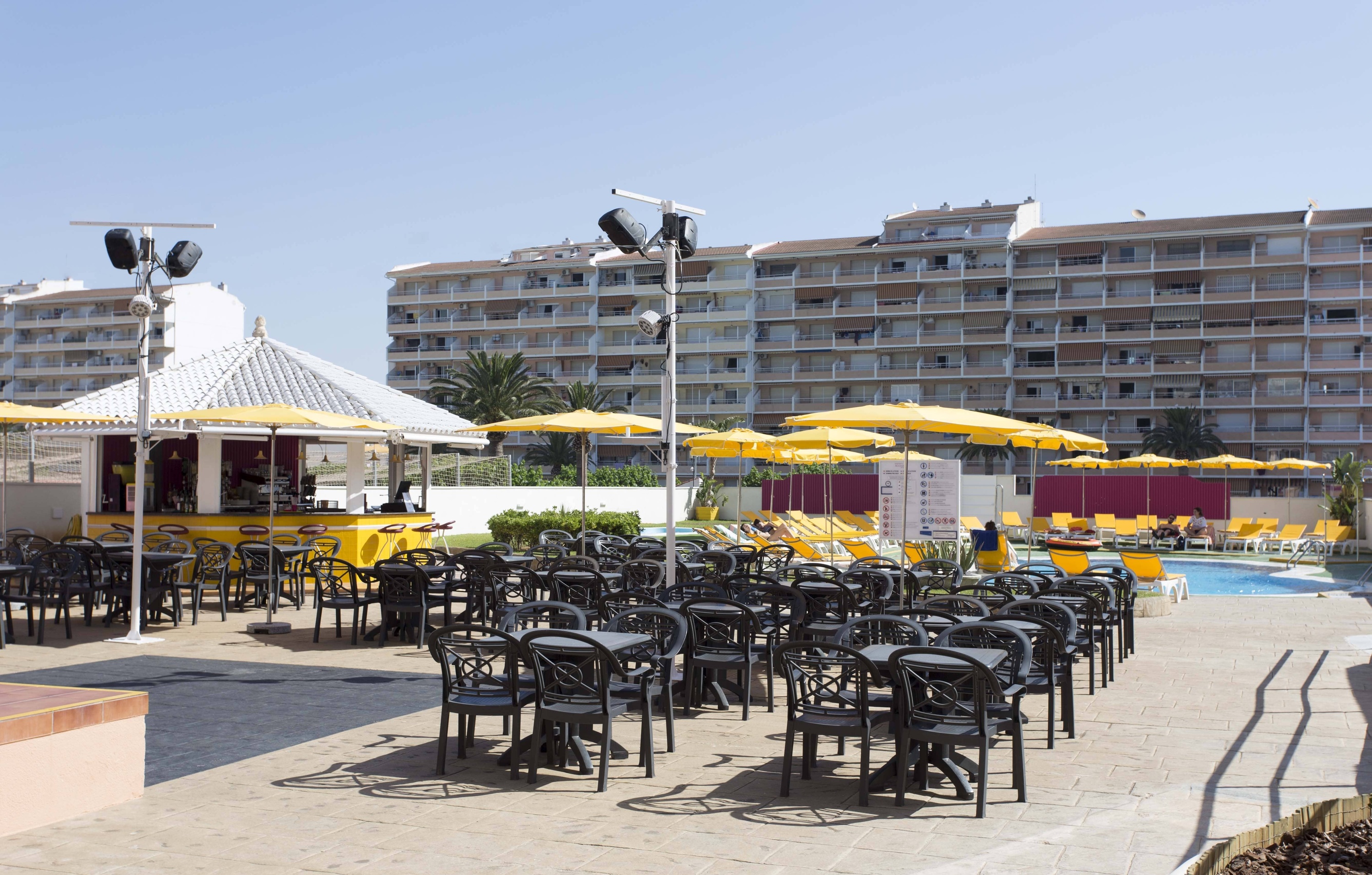 una piscina rodeada de mesas y sillas y sombrillas amarillas