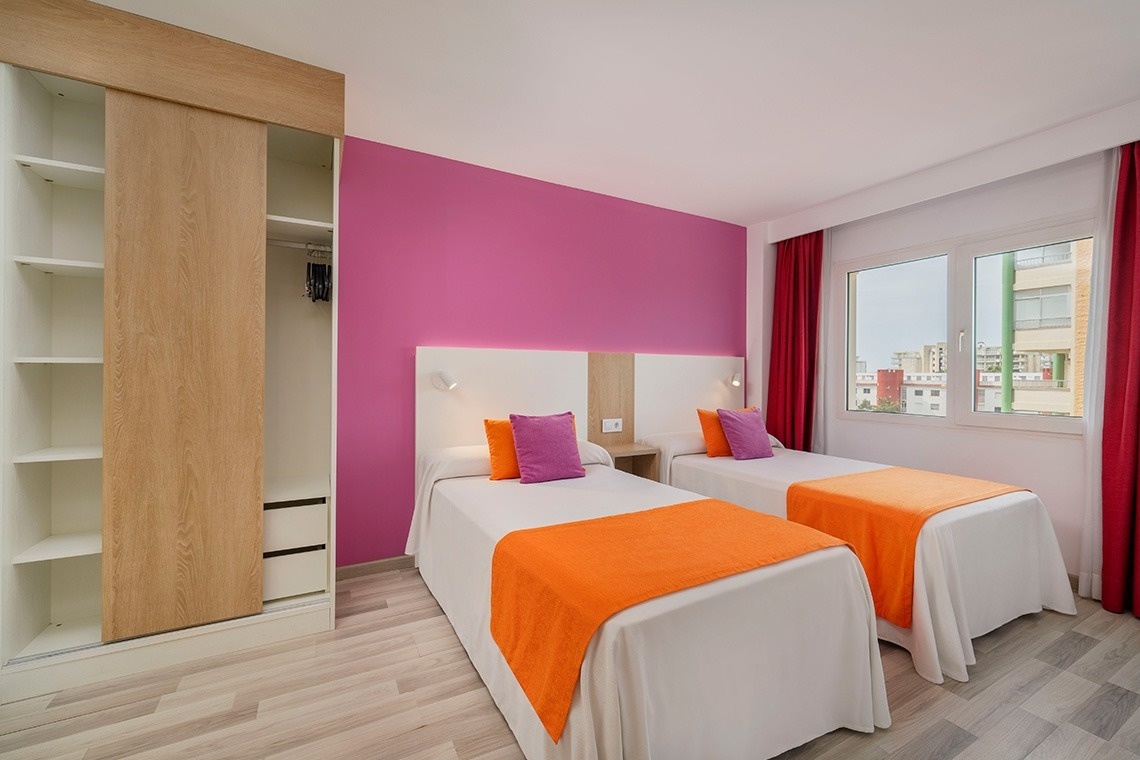 a bedroom with two beds and a pink wall