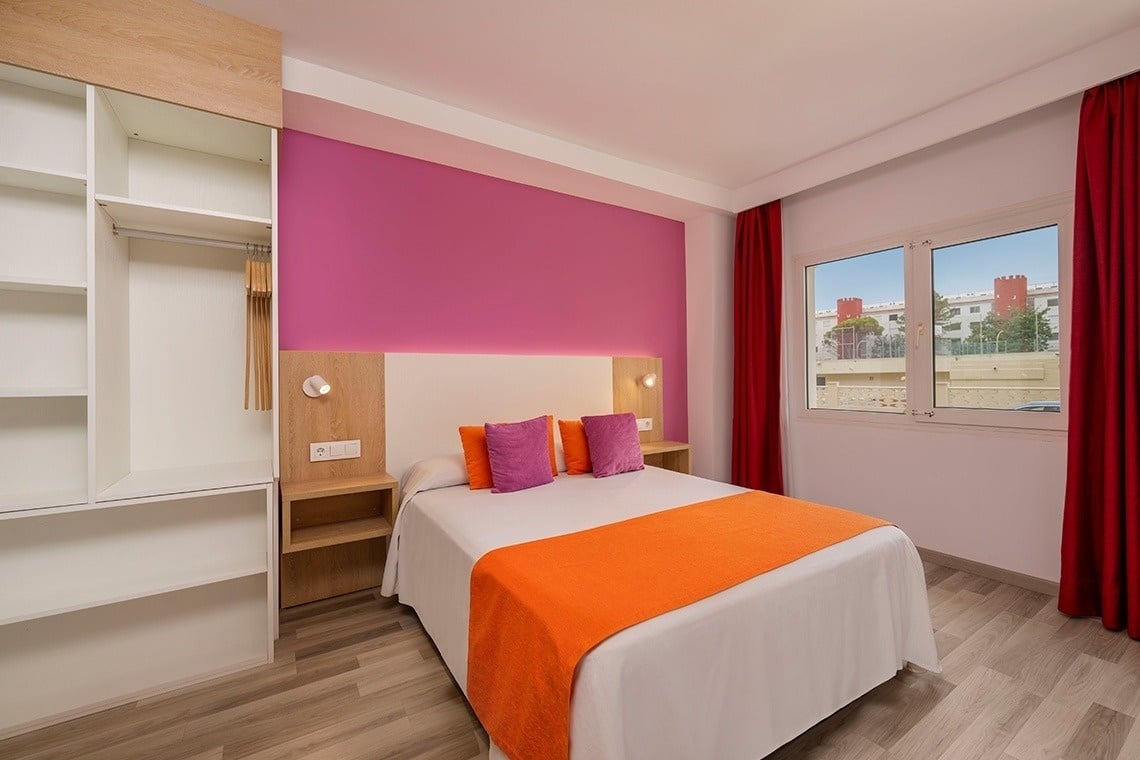 a bedroom with a bed and a pink wall