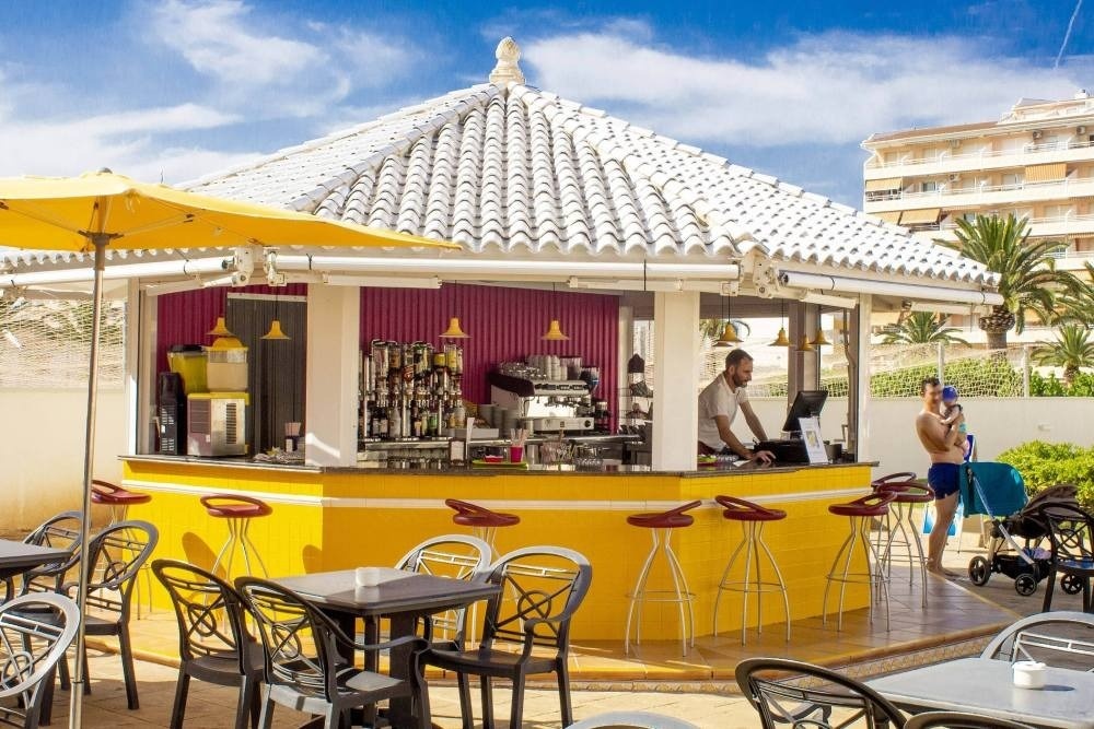 un hombre se sienta en el mostrador de un bar con mesas y sillas