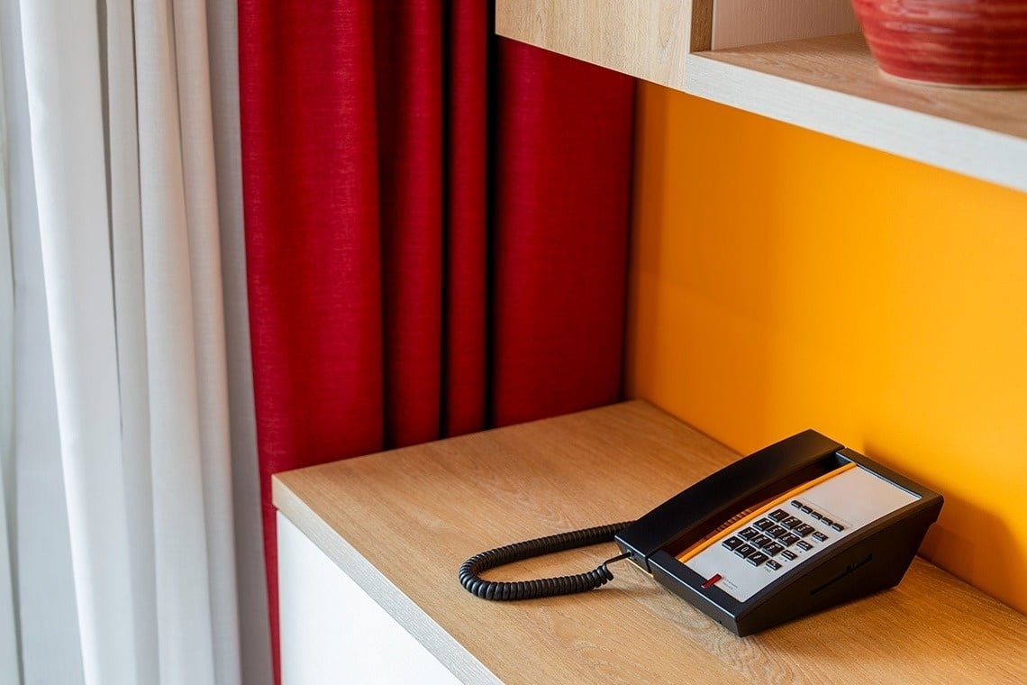a phone on a wooden table with a yellow wall behind it
