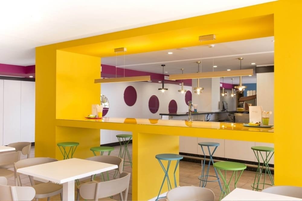 un restaurante con paredes amarillas y taburetes verdes