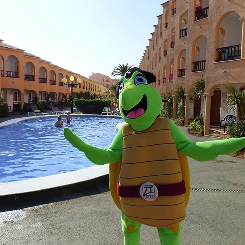 una mascota de tortuga está parada frente a una piscina
