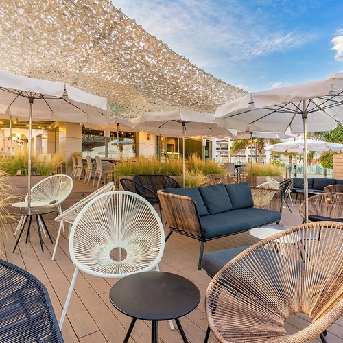 una terraza con sillas y mesas y un sofá y sombrillas