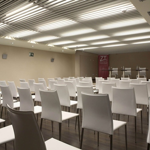 una sala de conferencias llena de sillas blancas y un cartel que dice zt