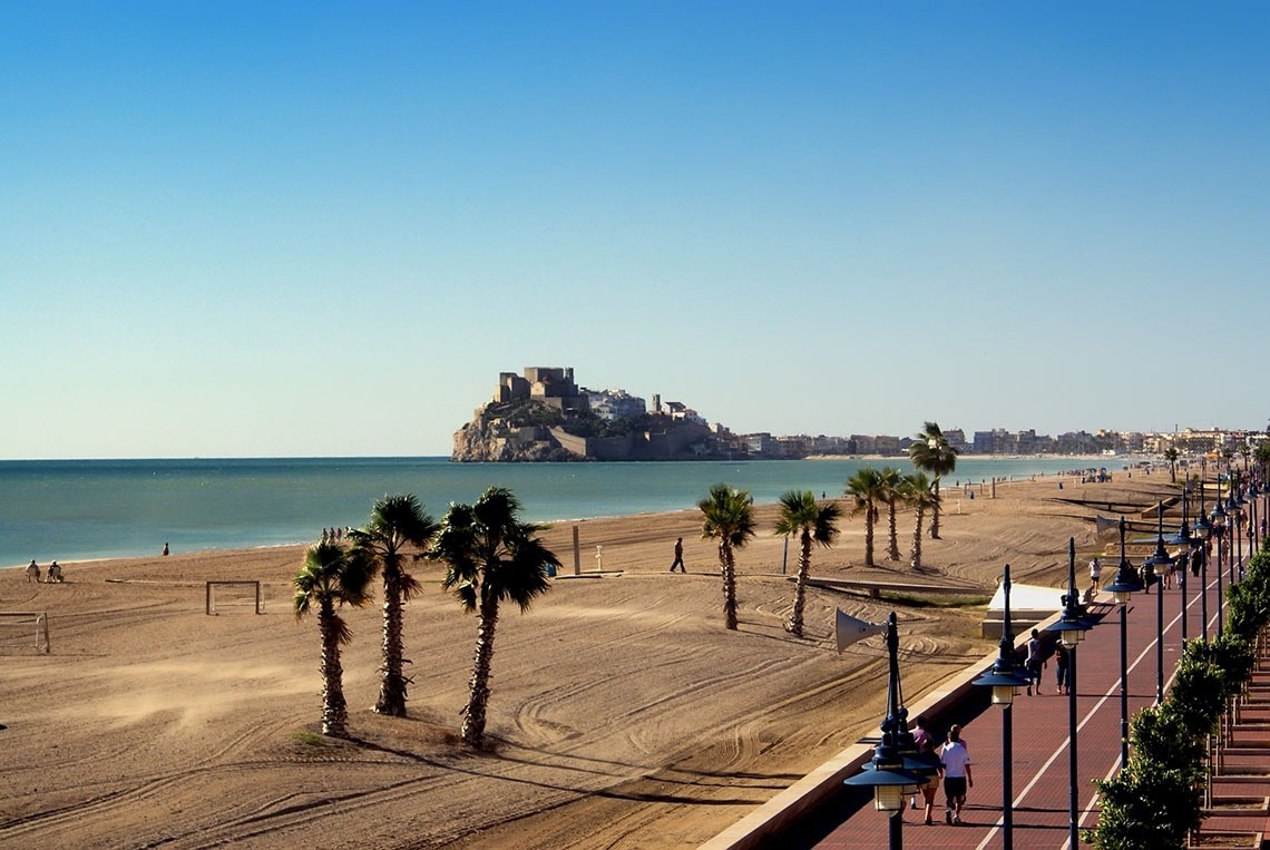 una playa con palmeras y un castillo en el fondo