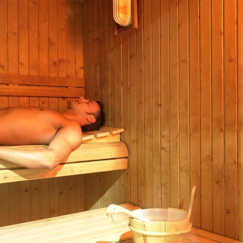 un hombre está acostado en una sauna de madera