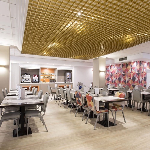 un restaurante lleno de mesas y sillas con un techo dorado