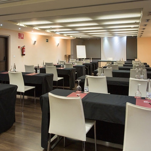 una sala de conferencias con mesas y sillas y un extintor en la pared