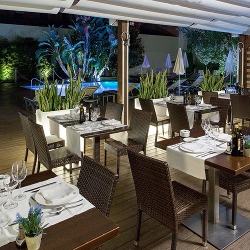 un restaurante con mesas y sillas y una piscina en el fondo