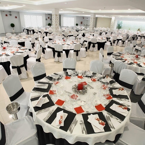 una habitación llena de mesas y sillas con cubiertas blancas y negras