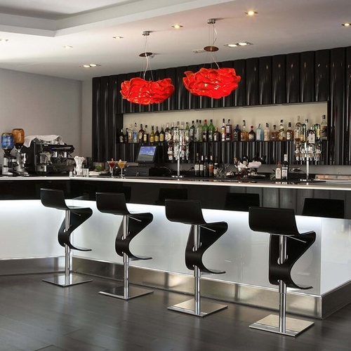 un bar con taburetes negros y luces rojas