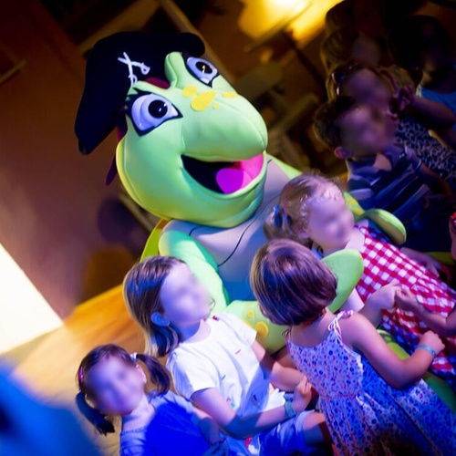 un grupo de niños bailan alrededor de una mascota de tortuga pirata