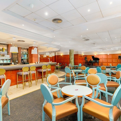 una habitación llena de mesas y sillas con un piano en el fondo