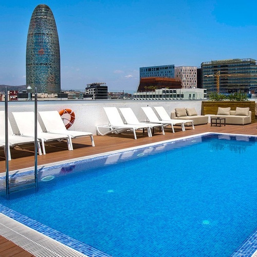 una piscina con sillas y una torre en el fondo