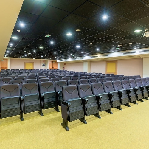 un auditorio lleno de asientos y un proyector en el techo