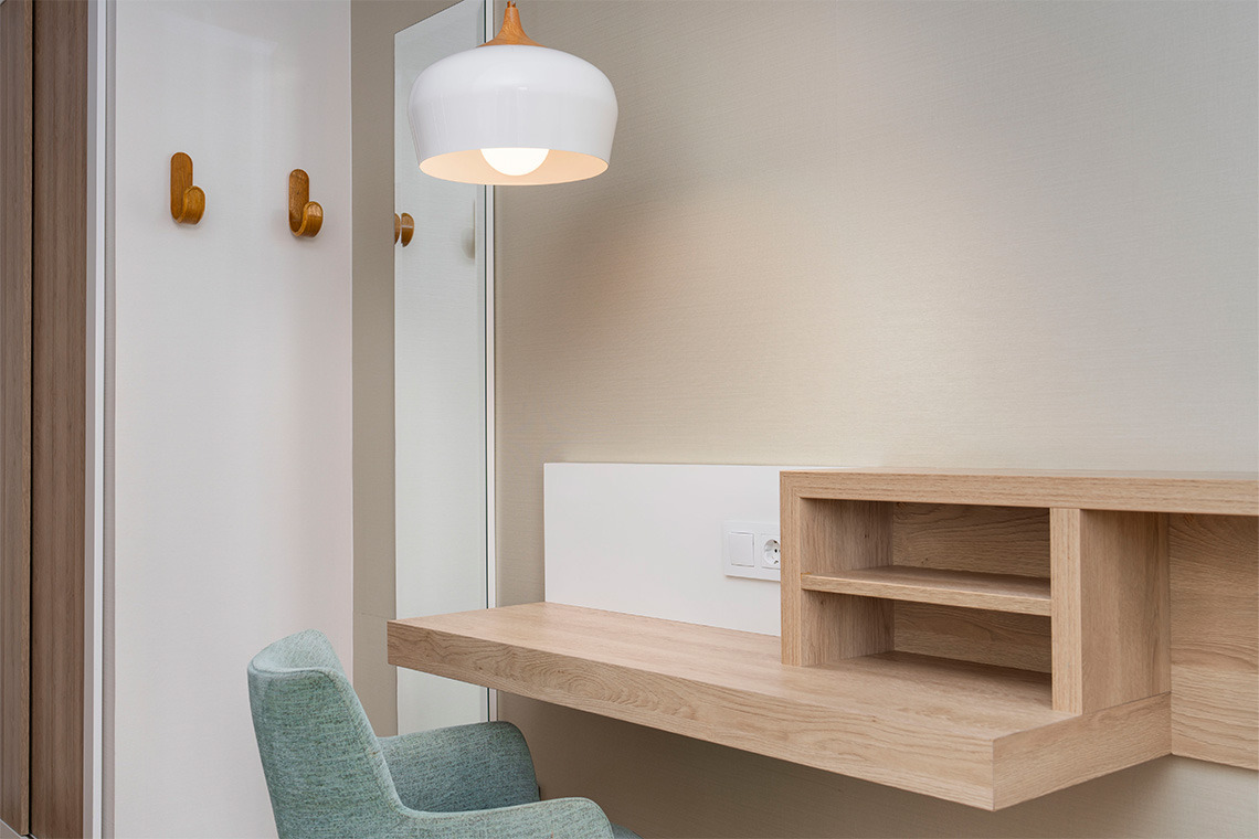 Estación de trabajo de madera y silla turquesa en habitación de hotel ZT: Golden Barcelona.